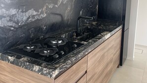 Eine moderne Küche mit schwarzem Marmorarbeitsplatz, Holzschränken und einem eingebauten Gasherd.