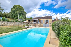 A swimming pool with lounge chairs, a stone wall, and a house in the background. - Charming House in Périgord with Large Private Pool (Tursac)