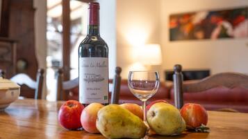 Une bouteille de vin, un verre et des fruits sur une table.