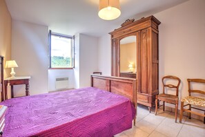 A bedroom with a bed, a wooden wardrobe, a chair, a desk with a lamp, and a window. - Charming House in Périgord with Large Private Pool (Tursac)