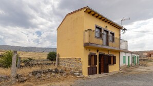 A two-story building with a balcony, a stone wall, and a gravel driveway. - Casa Raspa Country House – Nature and Charm in Ávila (Baterna)