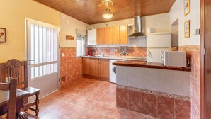 A kitchen with wooden cabinets, a built-in oven, a sink, and a microwave. - Casa Raspa Country House – Nature and Charm in Ávila (Baterna)