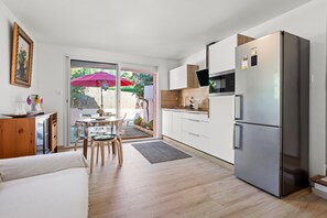 Una cucina moderna con frigorifero in acciaio inossidabile, mobili in legno e zona pranzo con tavolo e sedie.
