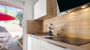 Une cuisine moderne avec un plan de travail en bois, des armoires blanches et un parasol rouge à l’extérieur.