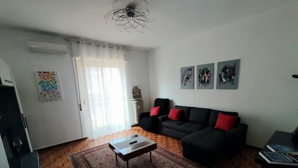 A living room with a sofa, a coffee table, a rug, and artwork on the wall.