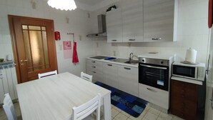 A kitchen with white cabinets, a stove, a microwave, and a sink.