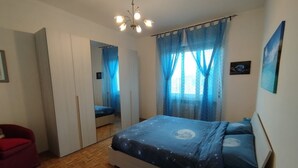 A bedroom with a bed, a red chair, a wardrobe, and a mirror.