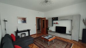 A living room with a sofa, a coffee table, a TV, and a patterned rug.