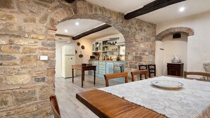 Un coin repas rustique avec une table en bois, des chaises et un mur en pierre.