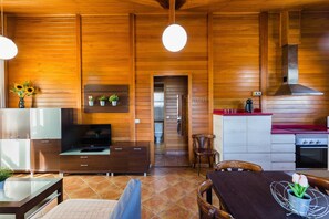 A wooden interior with a dining area, kitchen, and a TV. - Holiday Home 'La Tramuntana' with Private Terrace, Wi-Fi and Air Conditioning (el Marenyet)