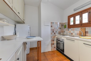 A kitchen with white cabinets, a tiled backsplash, a sink, and a countertop.