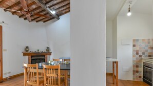 Een eethoek met houten stoelen, een tafel en een open haard.