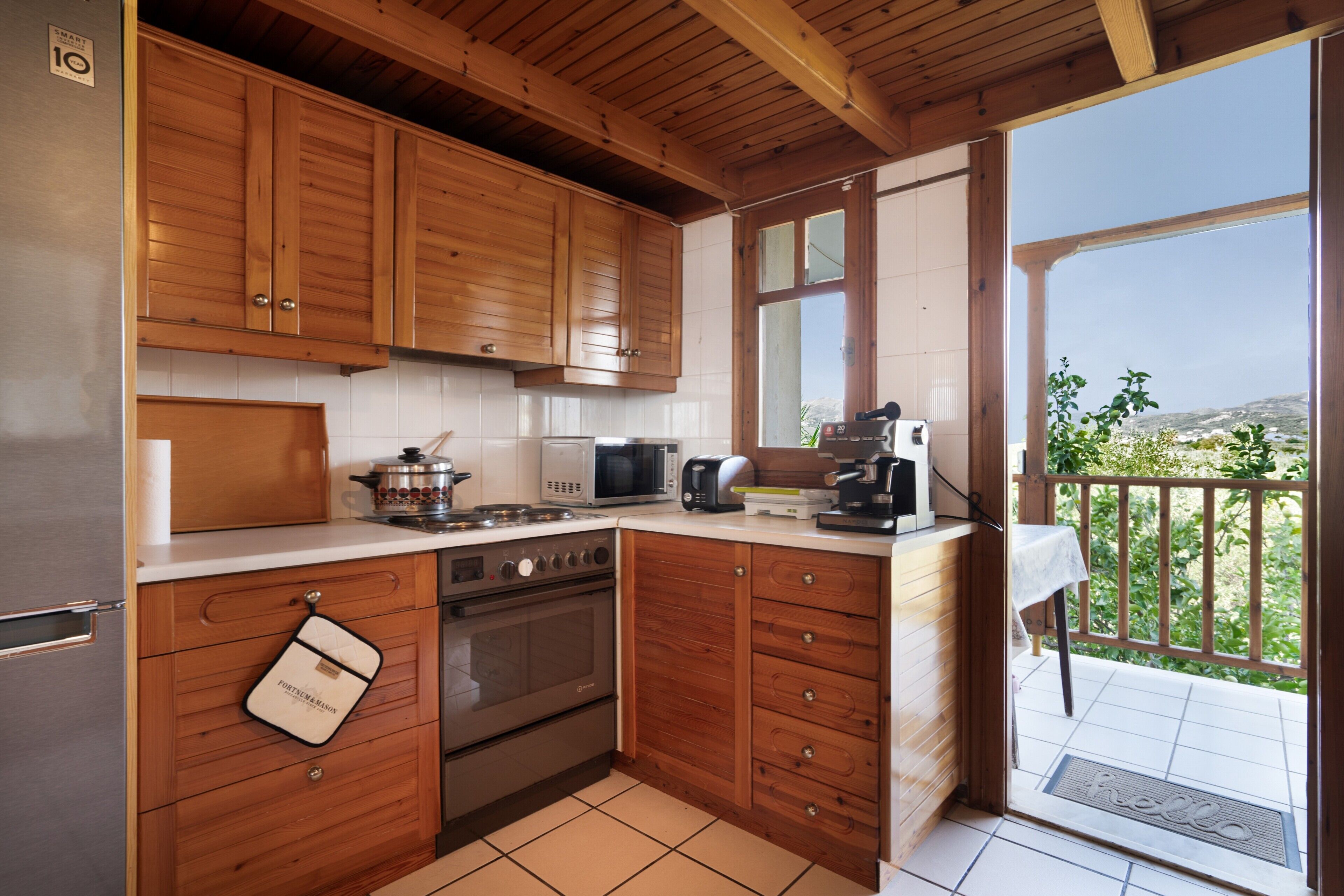 A kitchen with wooden cabinets, a stove, microwave, and a view of the outdoors.