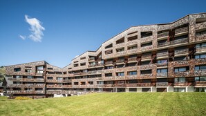 A multi-story hotel with a brick facade, balconies, and a grassy courtyard. - Apartment 'Les Pralyssimes 462' with Mountain View, Private Terrace and Wi-Fi (Taninges)