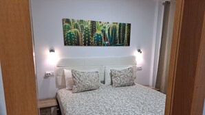 Un dormitorio con cama, dos lámparas de noche, un cuadro en la pared y una puerta de madera.
