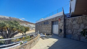 Un edificio de piedra con un letrero que dice 'Puerto Feliz', una terraza empedrada y palmeras.