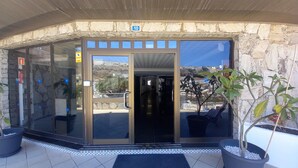 Una entrada de edificio con puerta de cristal, pared de piedra y vista panorámica de la ciudad.