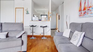 A modern living room with two grey sofas, a coffee table, and a kitchen area in the background. - Apartment 'Les 2 Tours La Rochelle' with Balcony and Wi-Fi (La Rochelle)