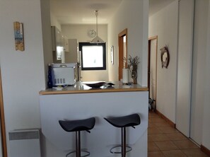 A kitchen with a microwave, sink, and two bar stools.