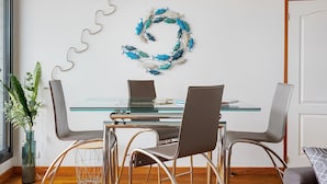 A modern dining area with a glass table, metal chairs, and a decorative wall piece. - Apartment 'Les 2 Tours La Rochelle' with Balcony and Wi-Fi (La Rochelle)