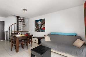 Un salon moderne comprenant un coin repas, un escalier et un tableau accroché au mur.