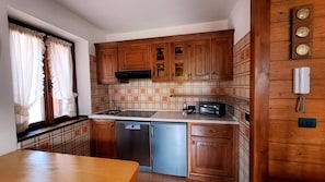 Une cuisine compacte avec des meubles en bois, un lave-vaisselle, un grille-pain et une fenêtre avec des rideaux.