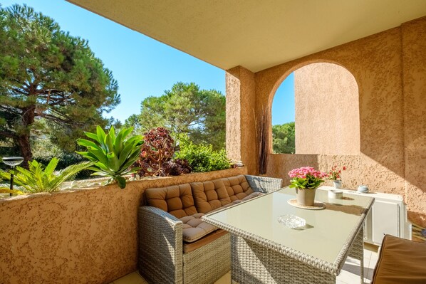 An outdoor patio with a wicker sofa, a glass table, and potted plants. - Apartment 'Vaugrenier Presidences' with Lake View, Wi-Fi and Air Conditioning (Villeneuve-Loubet)