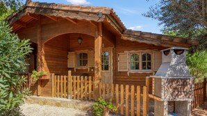 Een houten hut met een veranda, schoorsteen en een omheind gebied.