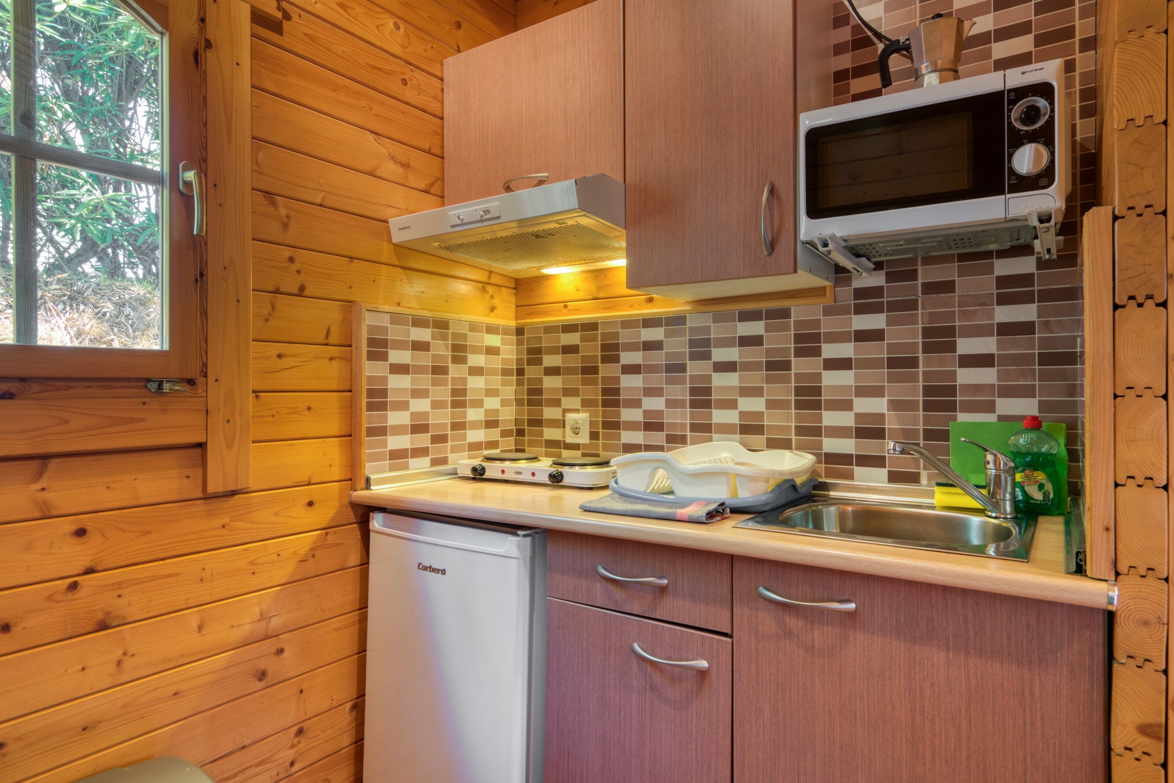 Una cocina compacta con armarios de madera, microondas, tostadora y lavavajillas.