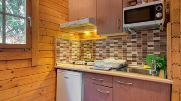Una cocina compacta con armarios de madera, microondas, tostadora y lavavajillas.