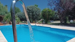 Una piscina con una escalera metálica y una superficie de agua azul cristalina.