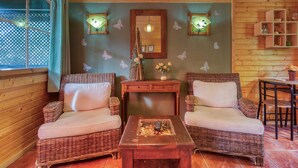 A cozy room with wicker furniture, a fireplace, and wall-mounted lights.