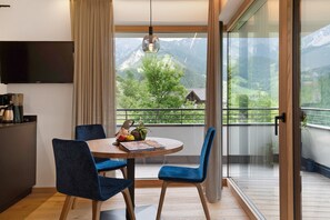 A dining area with a table, chairs, and a view of mountains through a large window.