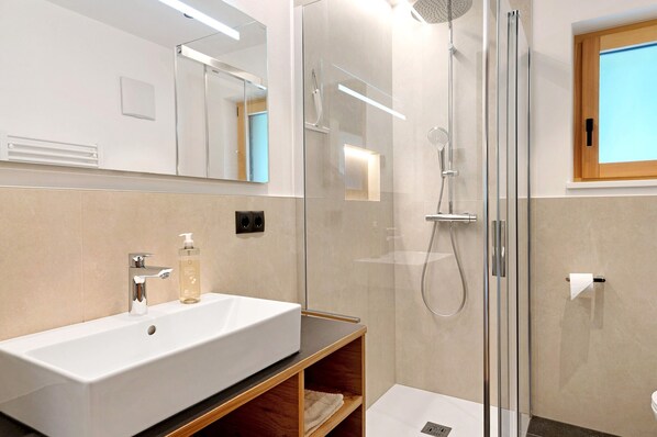 Une salle de bain moderne avec un grand lavabo blanc, une douche en verre et un meuble-lavabo en bois.