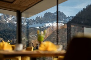Une vue sur la montagne par la fenêtre, un plafond en bois et une table avec un vase.