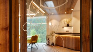 Ein Empfangsbereich mit einem Holzbüro, einem gelben Sessel und Blick auf Grünflächen.