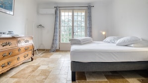 Quarto com cama, cômoda e janela com cortinas.