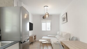 Eine moderne Küche mit einem Edelstahlkühlschrank, einem Holztisch und einem weißen Sofa.