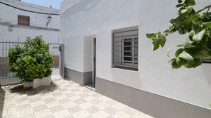 Ein Innenhof mit einem Blumentopf, einem Fenster und einem gefliesten Boden.