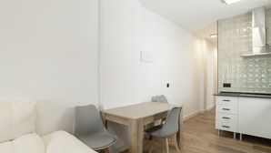 Eine moderne Küche mit Holztisch und -stühlen, einer weißen Arbeitsplatte und einer gefliesten Spritzschutzwand.