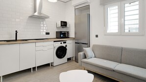 Een moderne keuken met witte kastjes, een wasmachine, een magnetron en een koelkast.