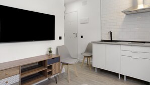 Een moderne keuken met witte kasten, een ingebouwde kookplaat en een flatscreen televisie aan de muur.