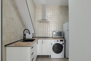 Une cuisine compacte équipée d’un lave-linge, d’un four à micro-ondes et d’un grille-pain.