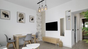 A modern living room with a dining area, a TV mounted on the wall, and a large mirror. - Apartment 'Apartamentos Habana 4' with Air Conditioning (Barbate)