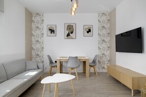 Un soggiorno moderno con un divano, un tavolo da pranzo, sedie, opere d'arte e una televisione.