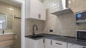A modern kitchen with a sink, microwave, and cabinets. - Apartment 'Apartamentos Habana 4' with Air Conditioning (Barbate)