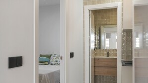 A hotel room with a bed, a bathroom with a mirror, and a wooden cabinet. - Apartment 'Apartamentos Habana 4' with Air Conditioning (Barbate)