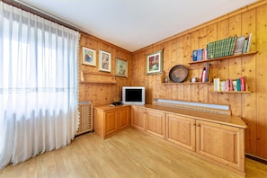 Une pièce aux murs en bois, avec un téléviseur posé sur un meuble en bois, des étagères à livres et des tableaux encadrés.