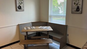 Ein Eckzimmer mit einer Bank, einem Tisch und zwei gerahmten Bildern an den Wänden.