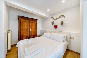 Une chambre à coucher avec un grand lit, une armoire en bois et des œuvres d’art décoratives au mur.